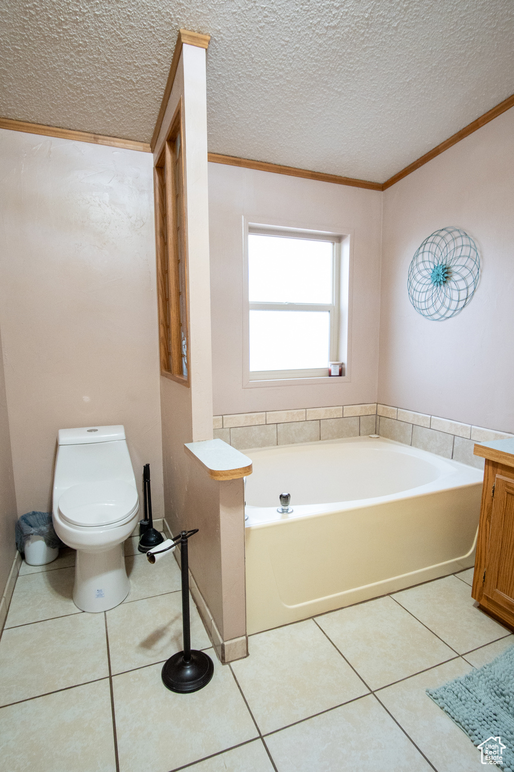 Bathroom with ornamental molding, a textured ceiling, tile patterned floors, and a bathtub