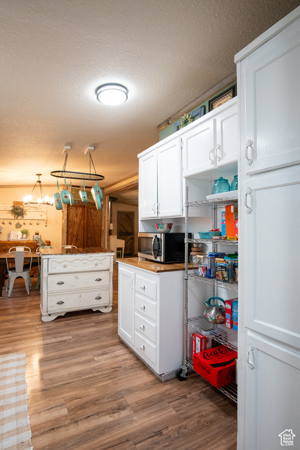 Kitchen with white cabinetry, a textured ceiling, and light wood-type flooring