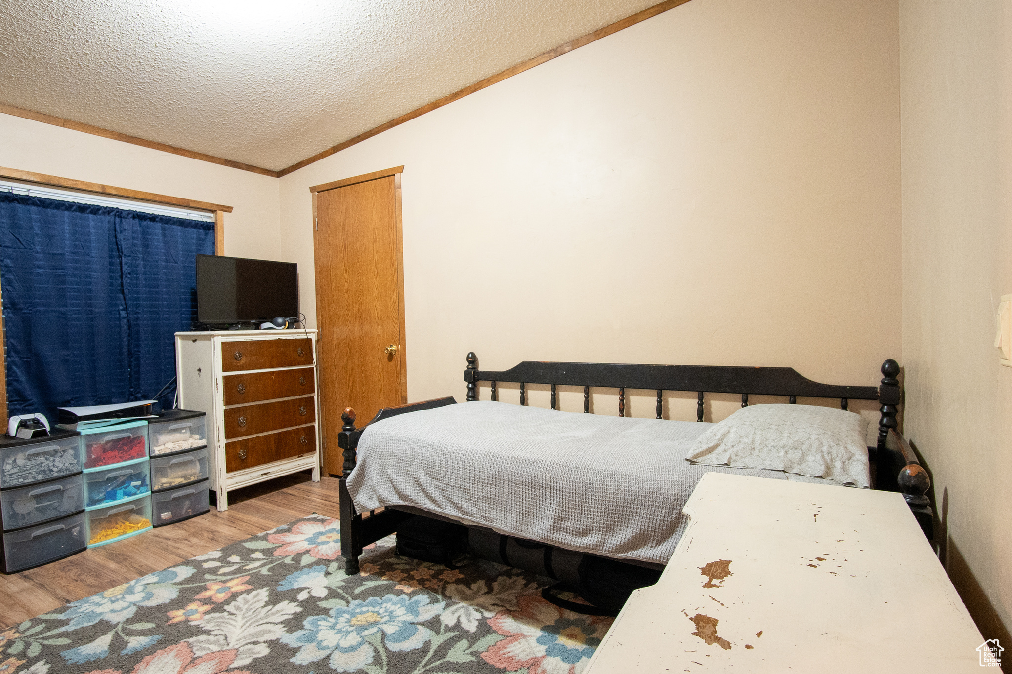 Bedroom featuring lofted ceiling, hardwood / wood-style floors, ornamental molding, and a textured ceiling