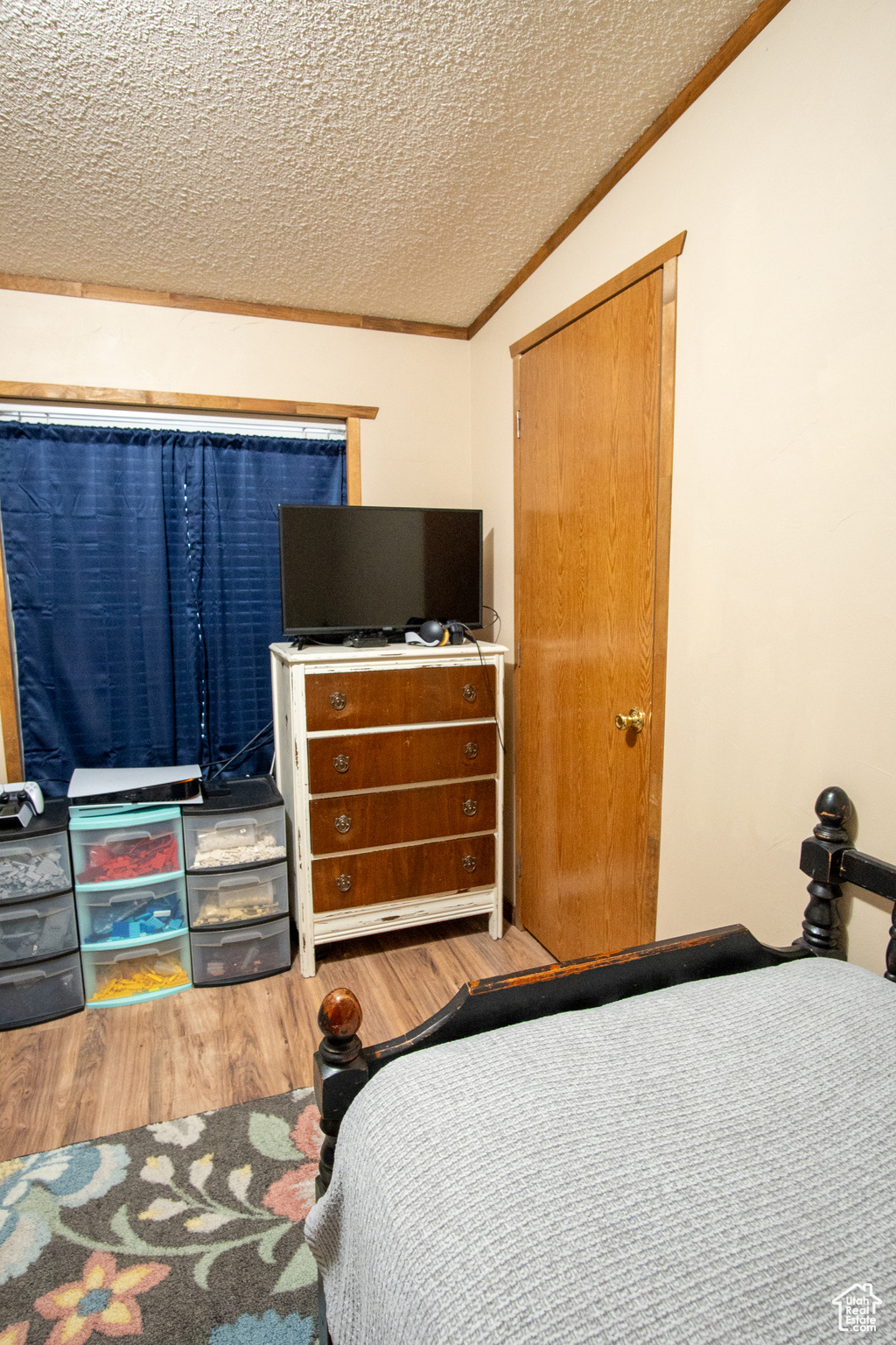 Bedroom featuring wood-type flooring, lofted ceiling, a textured ceiling, and crown molding