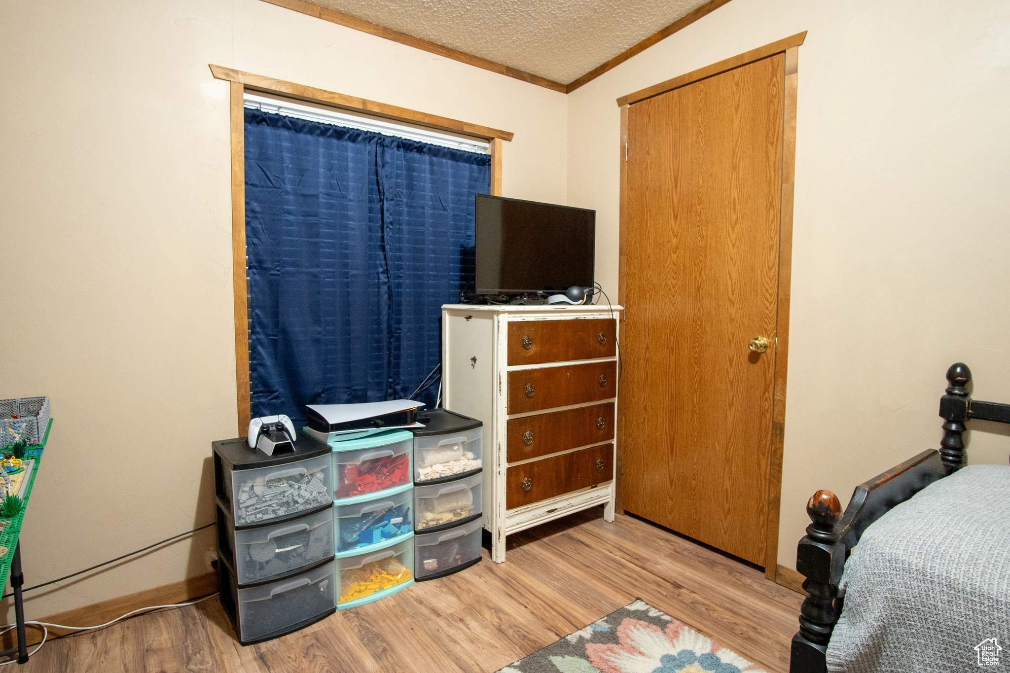 Bedroom featuring ornamental molding, a textured ceiling, and light wood-type flooring