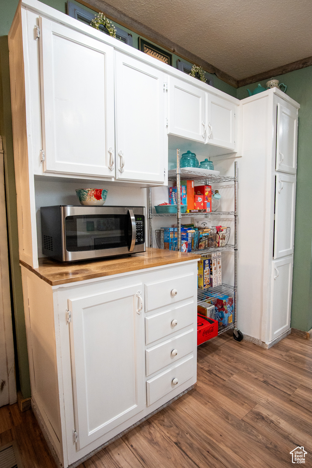 Kitchen featuring hardwood / wood-style floors, a textured ceiling, and white cabinets