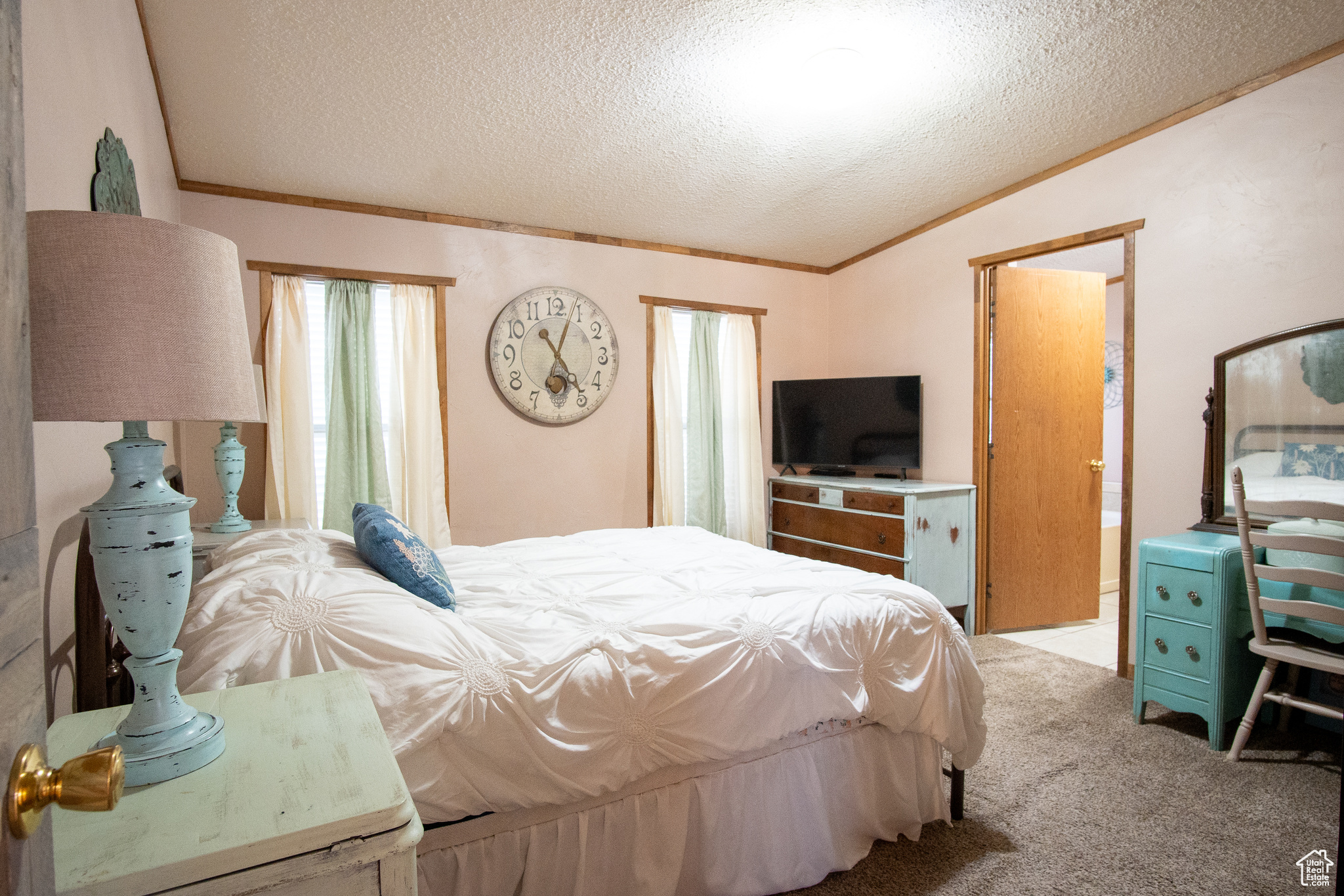 Bedroom featuring lofted ceiling, ornamental molding, light colored carpet, and a textured ceiling