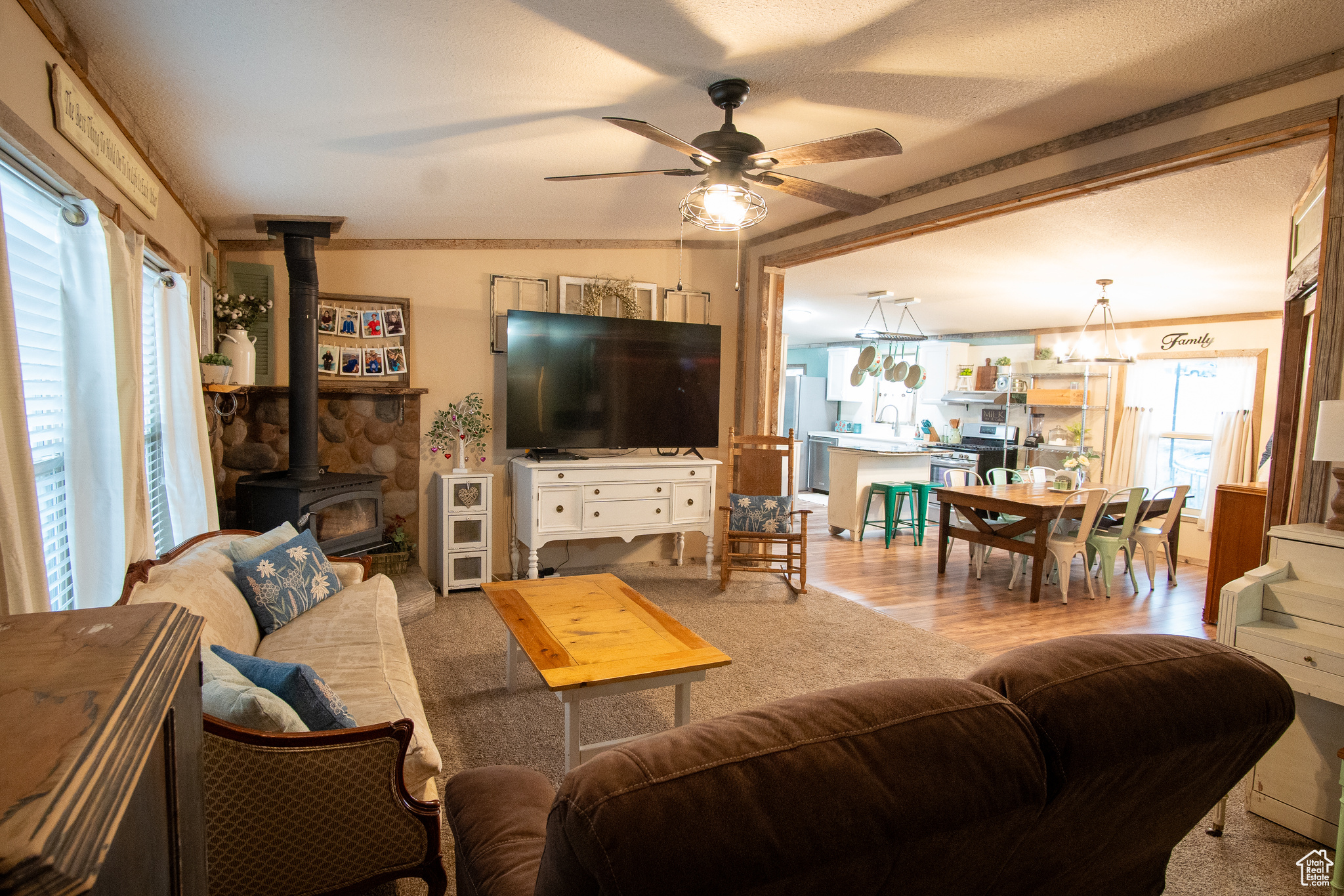 Living room featuring ceiling fan, wood-type flooring, a textured ceiling, and a wood stove