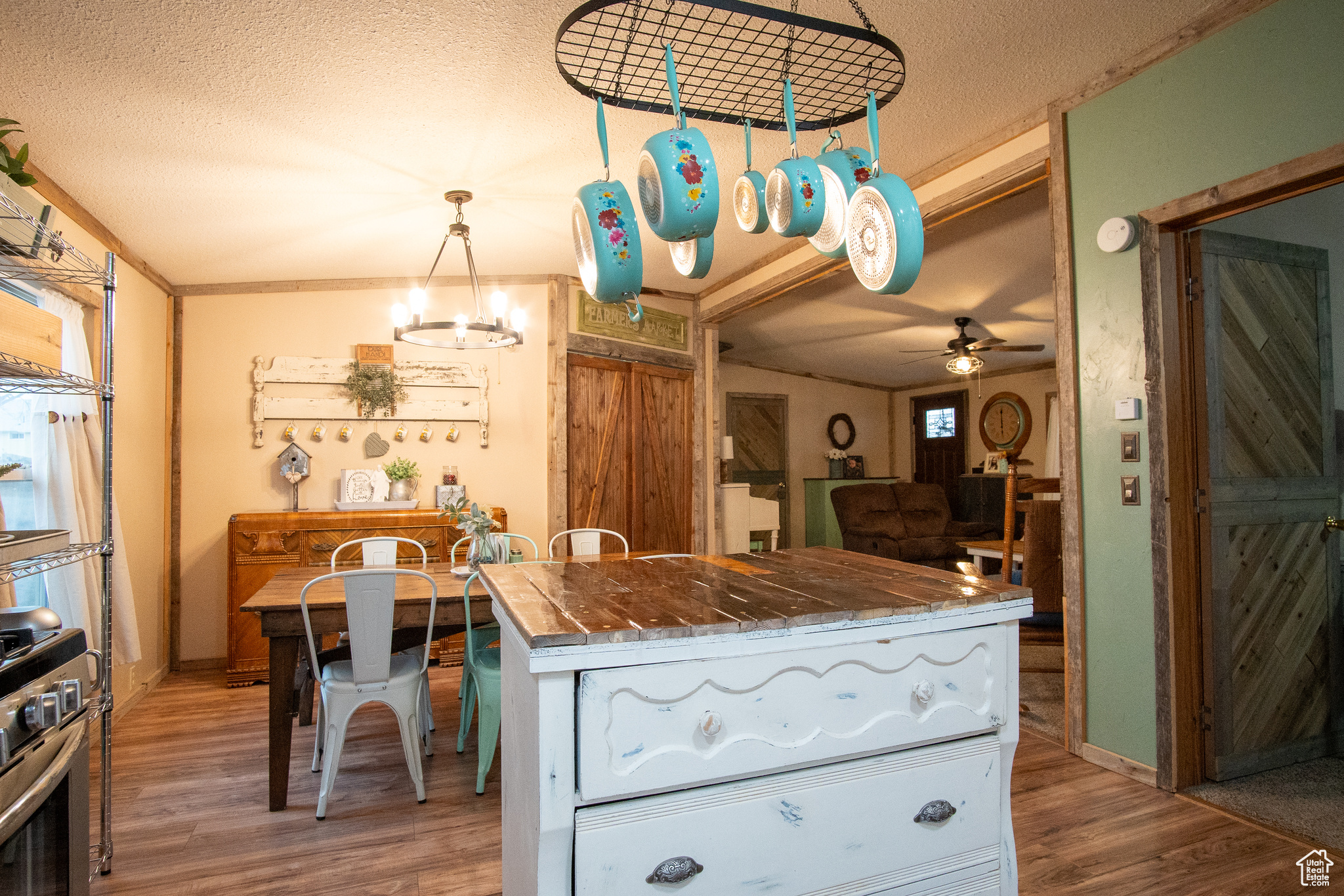 Kitchen featuring stainless steel gas range oven, light hardwood / wood-style flooring, hanging light fixtures, a textured ceiling, and ceiling fan with notable chandelier