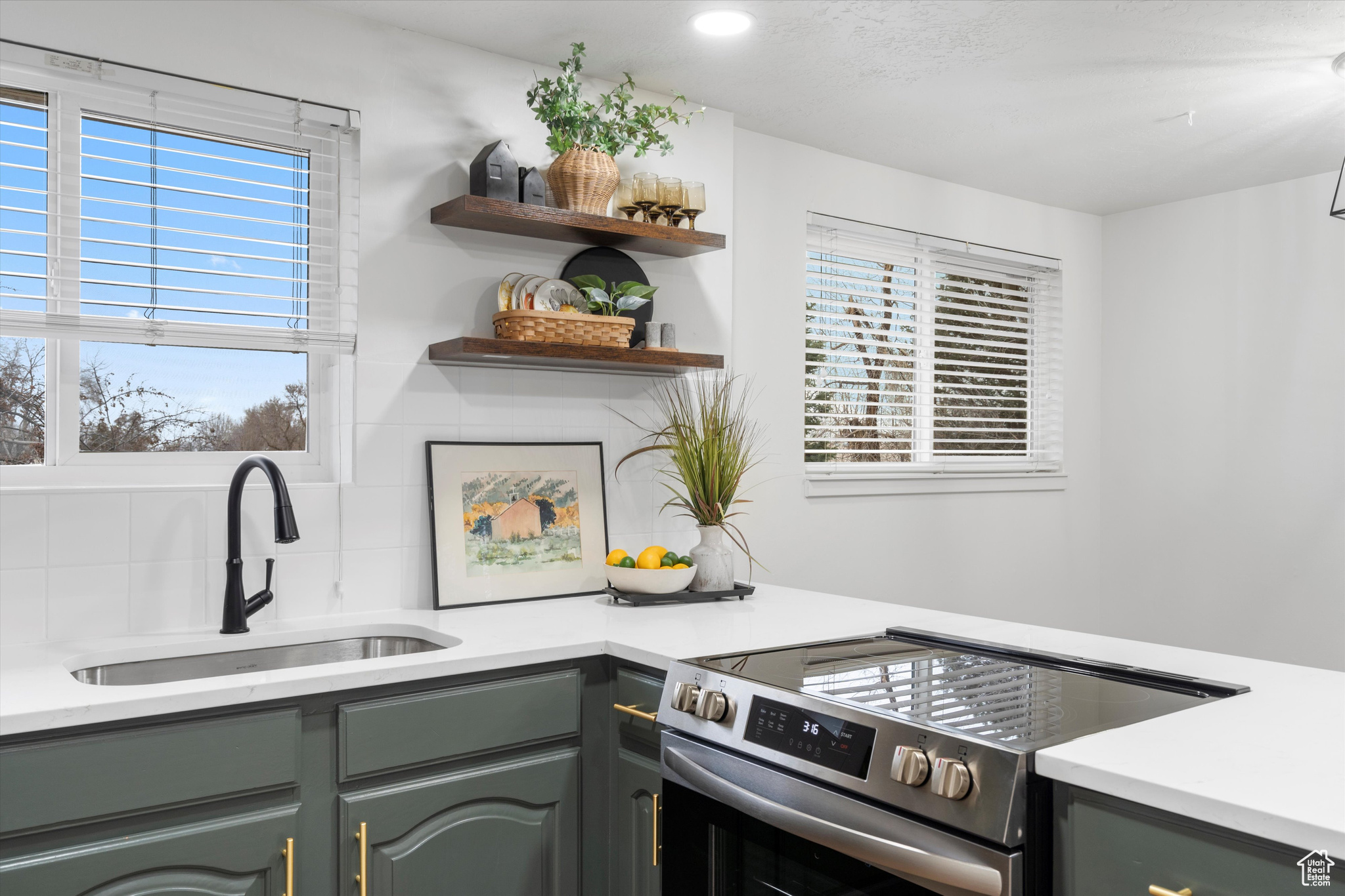 Kitchen featuring stainless steel electric stove, sink, and backsplash