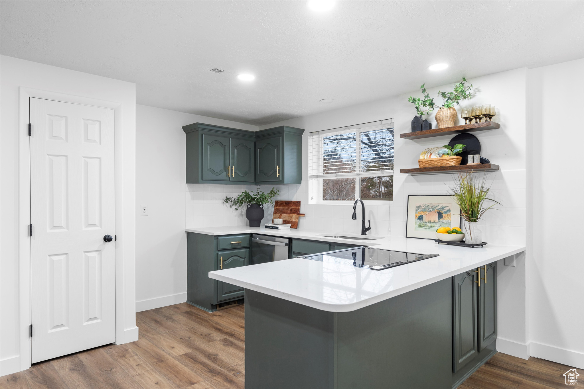 Kitchen with sink, dishwasher, dark hardwood / wood-style flooring, decorative backsplash, and kitchen peninsula