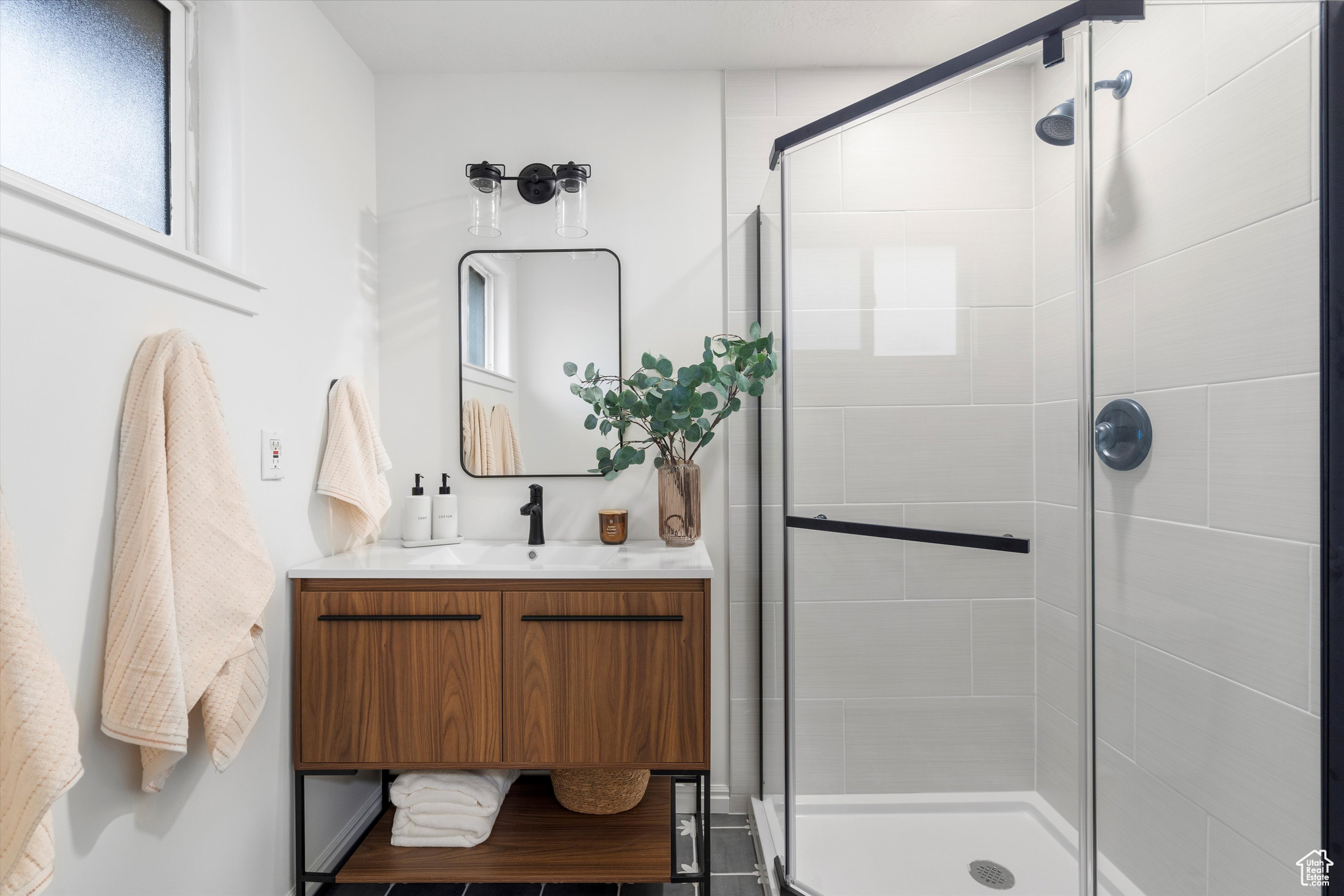 Bathroom with an enclosed shower, vanity, and plenty of natural light