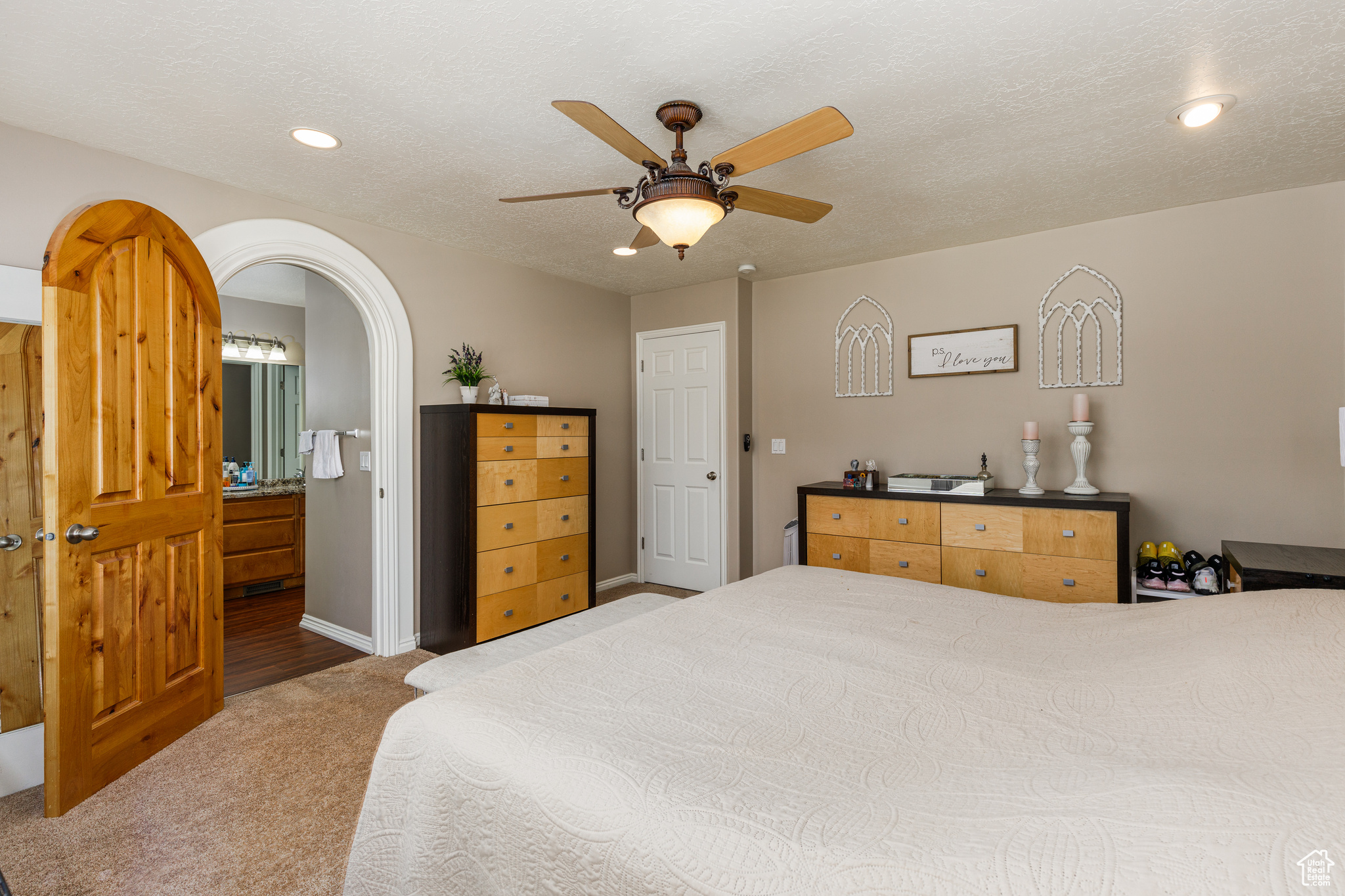 Bedroom with ceiling fan, carpet, a textured ceiling, and ensuite bath