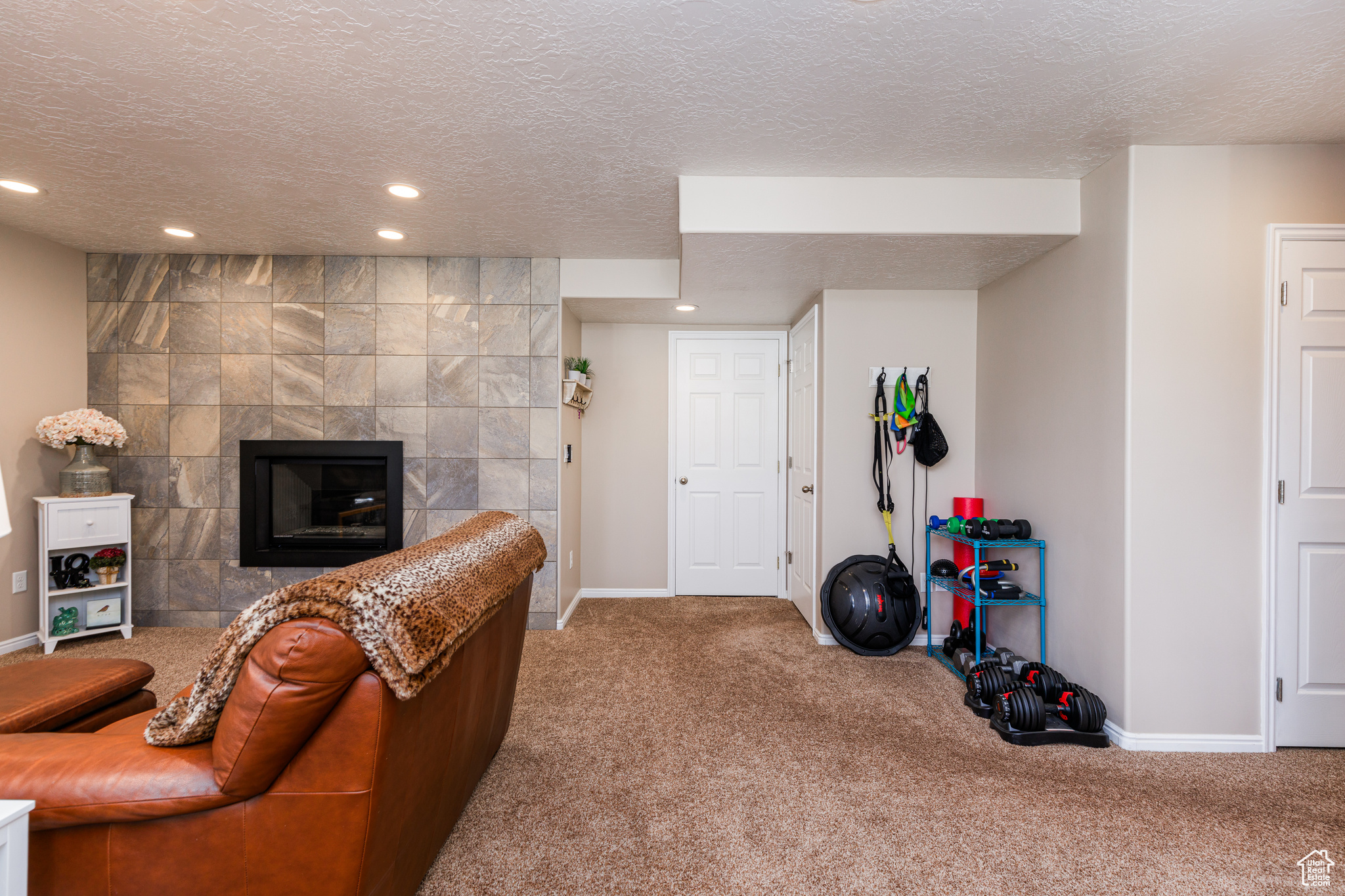 Carpeted living room featuring a tile fireplace and a textured ceiling