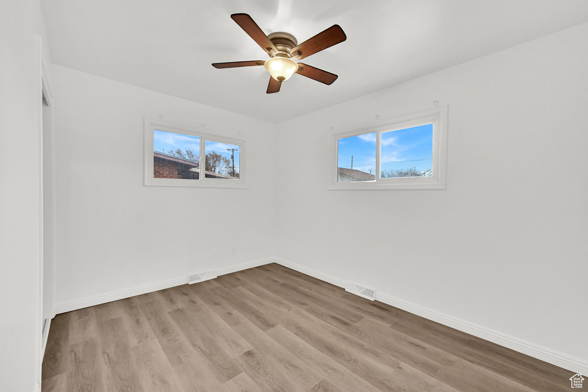 Empty room with ceiling fan and light wood-type flooring