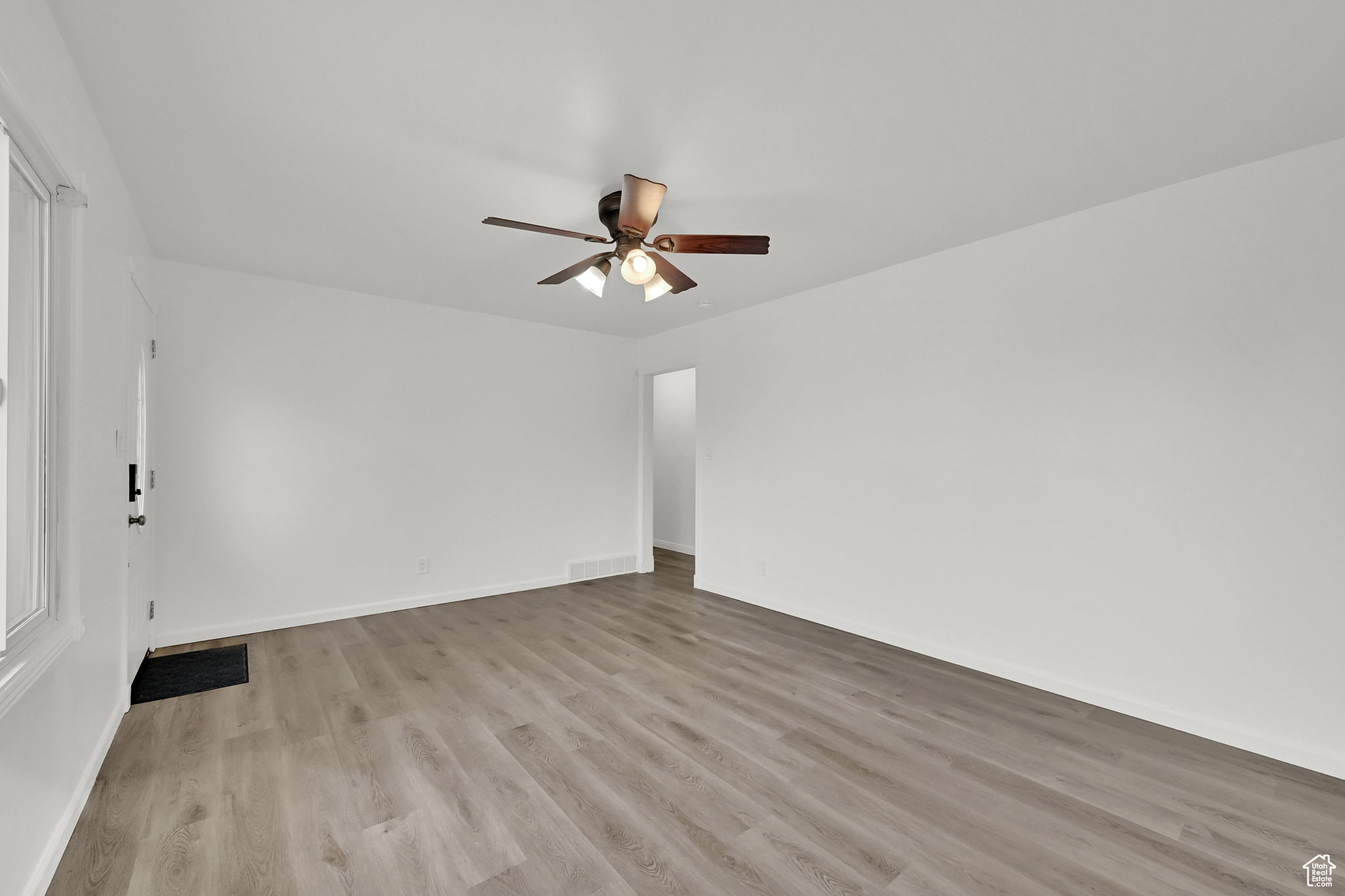 Empty room with ceiling fan and light hardwood / wood-style floors