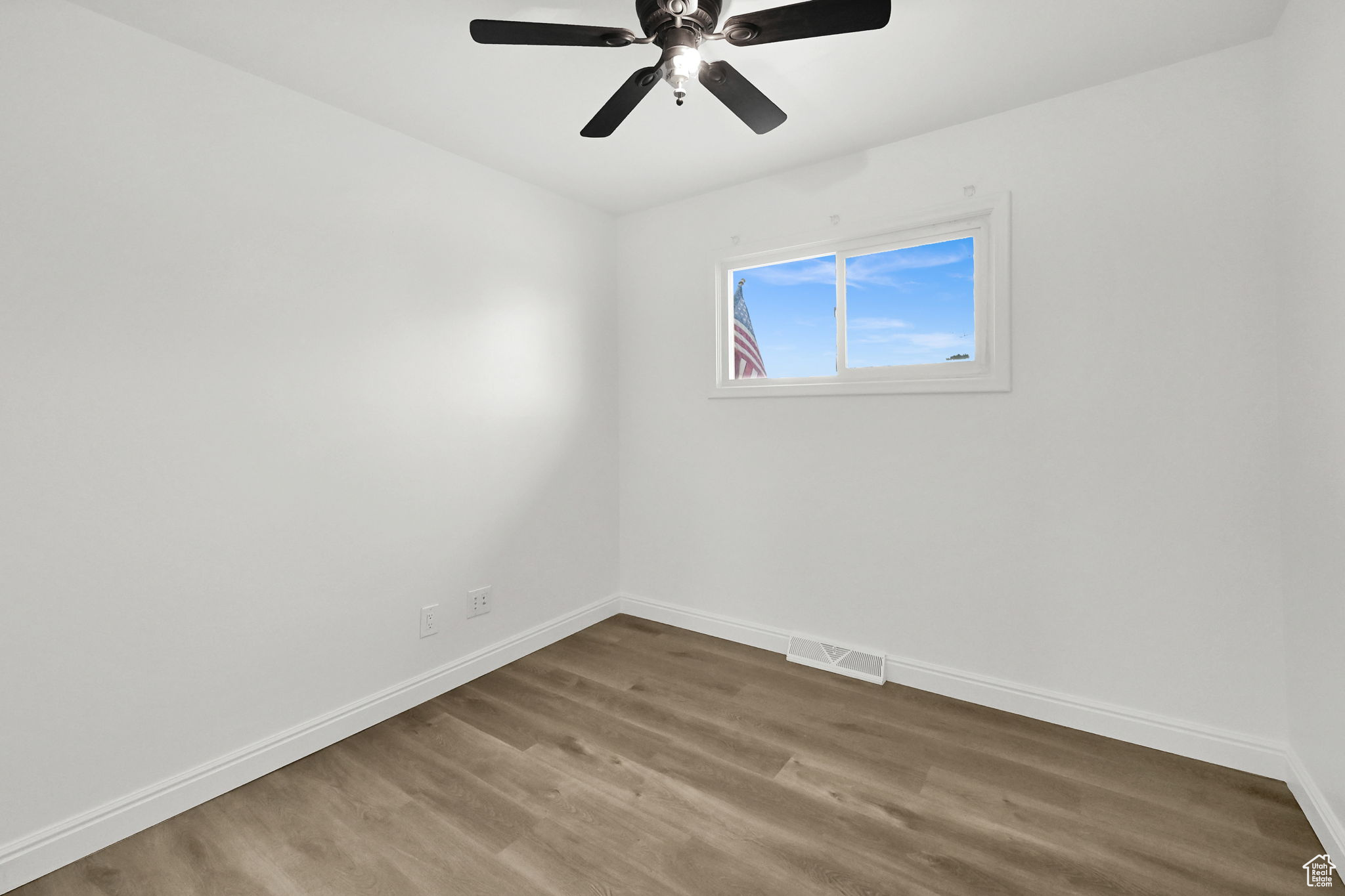 Empty room with ceiling fan and wood-type flooring