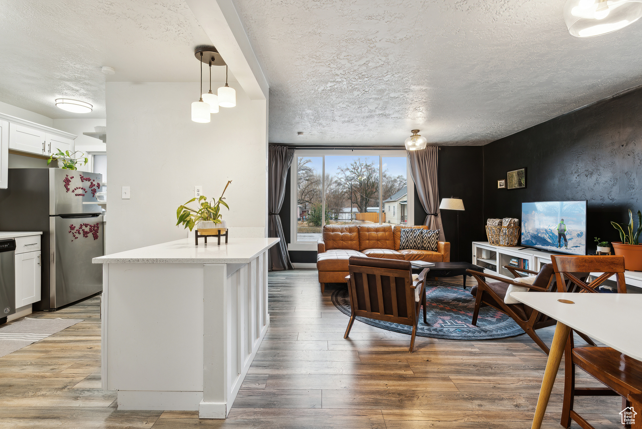 Kitchen with white cabinetry, pendant lighting, light hardwood / wood-style floors, and stainless steel appliances