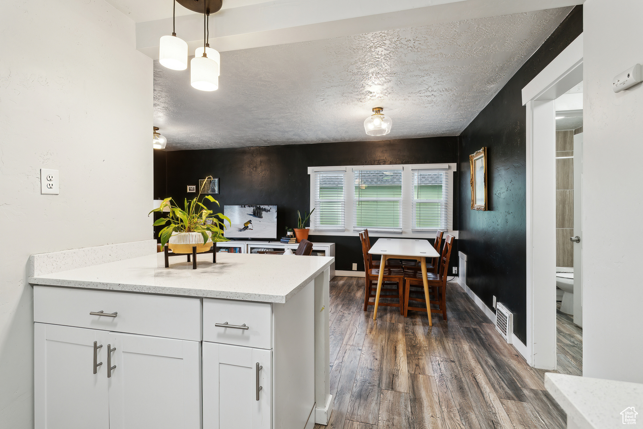 Kitchen featuring white cabinetry, dark hardwood / wood-style floors, a textured ceiling, and decorative light fixtures