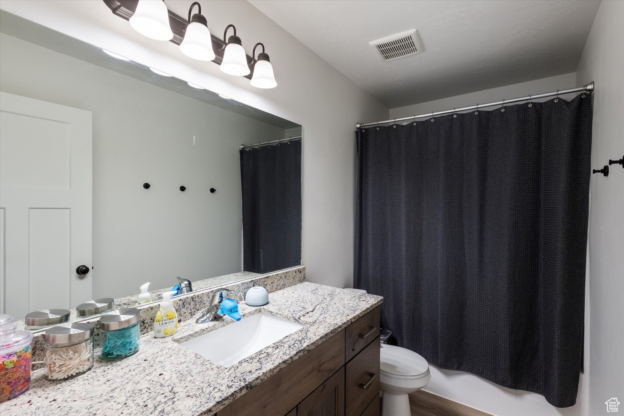 Full bathroom featuring vanity, toilet, and shower / tub combo with curtain