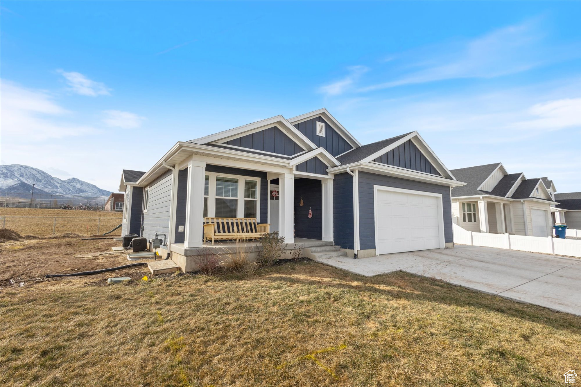 View of front of house featuring a mountain view, a garage, a front lawn, and a porch