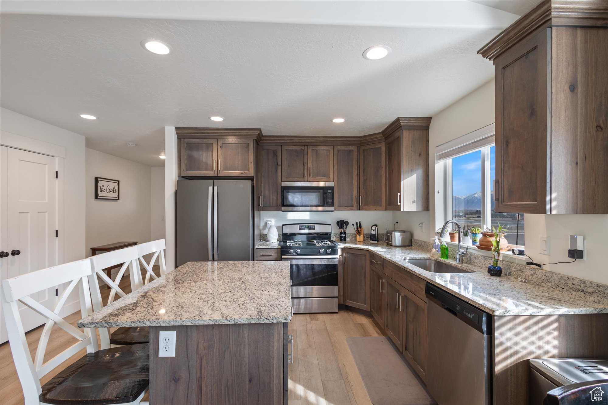 Kitchen featuring a kitchen bar, sink, a kitchen island, stainless steel appliances, and light stone countertops