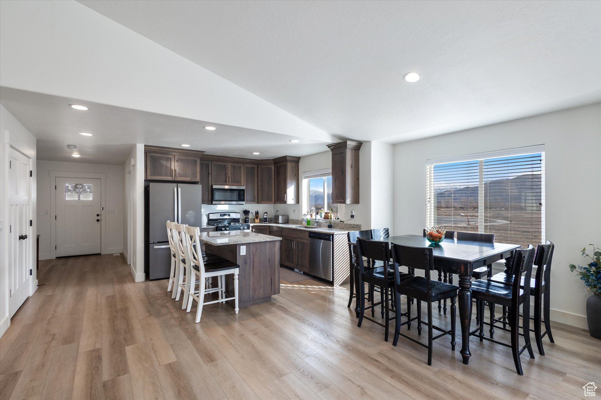 Kitchen featuring a breakfast bar area, vaulted ceiling, dark brown cabinets, a kitchen island, and stainless steel appliances