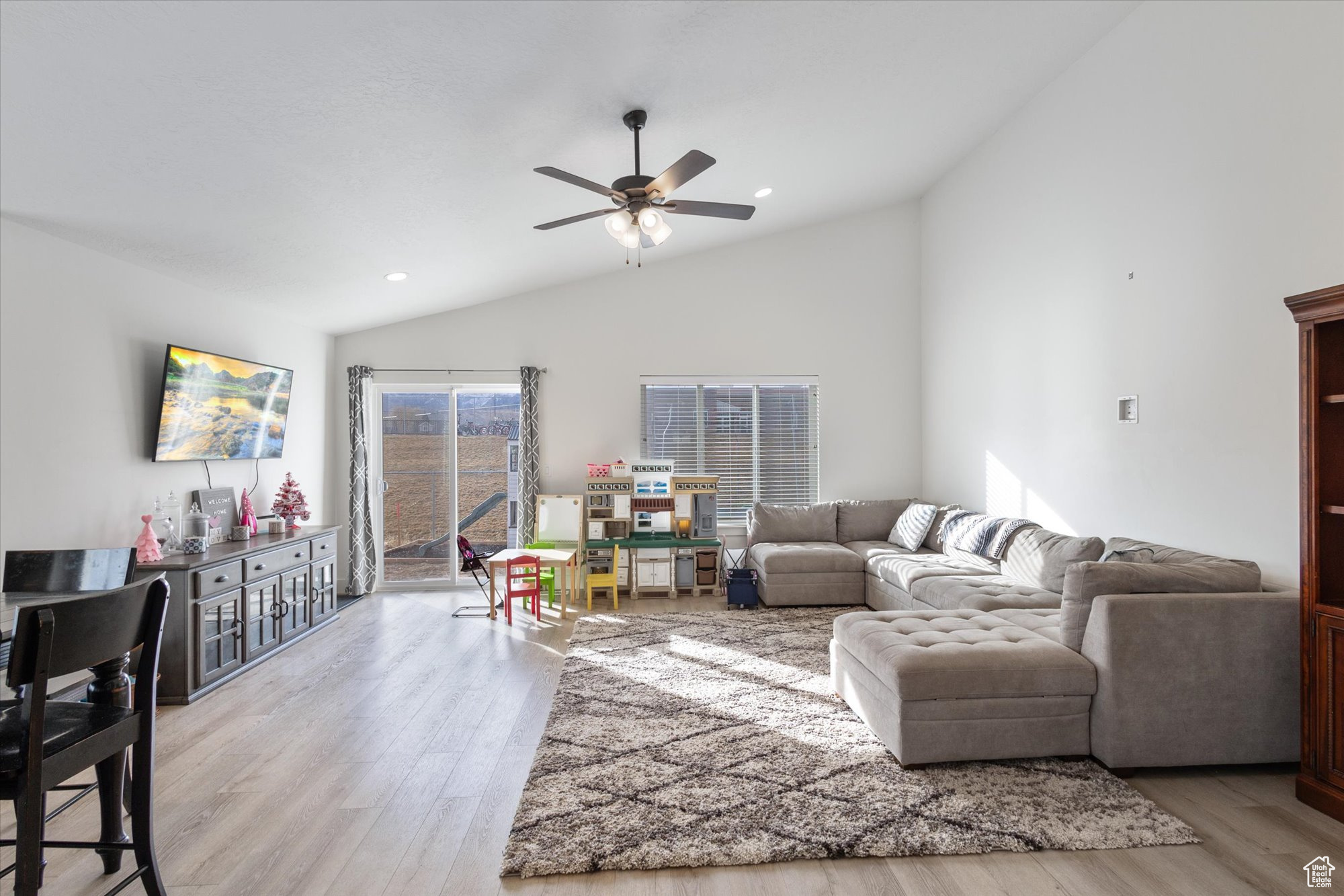 Living room featuring ceiling fan, vaulted ceiling, and light hardwood / wood-style flooring