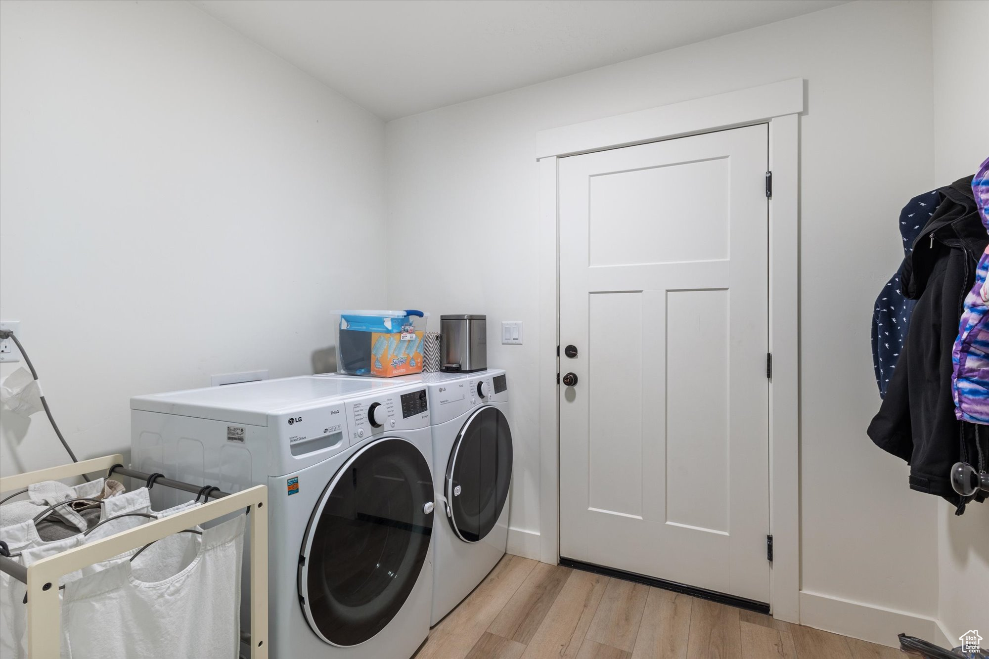 Clothes washing area with independent washer and dryer and light hardwood / wood-style flooring