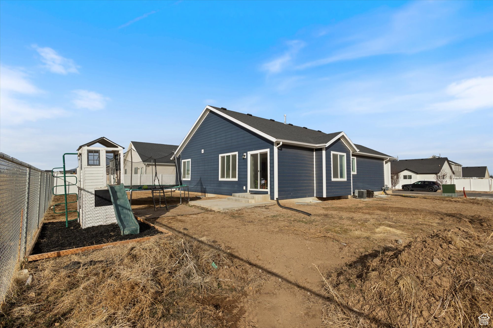 Back of property featuring a playground and a trampoline