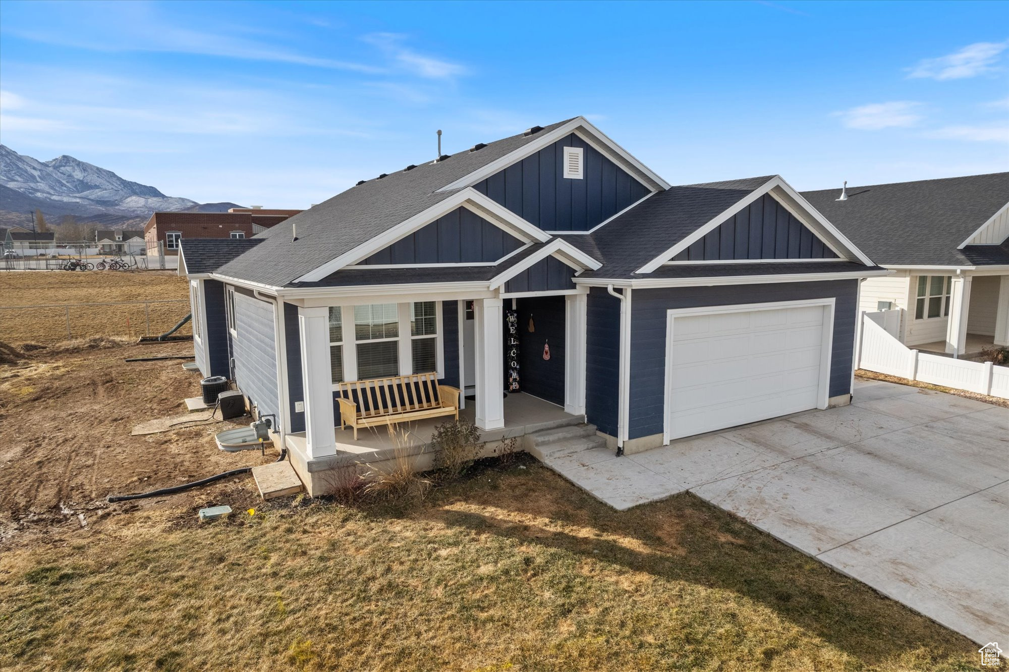 View of front of property featuring a porch, a garage, a mountain view, and a front yard