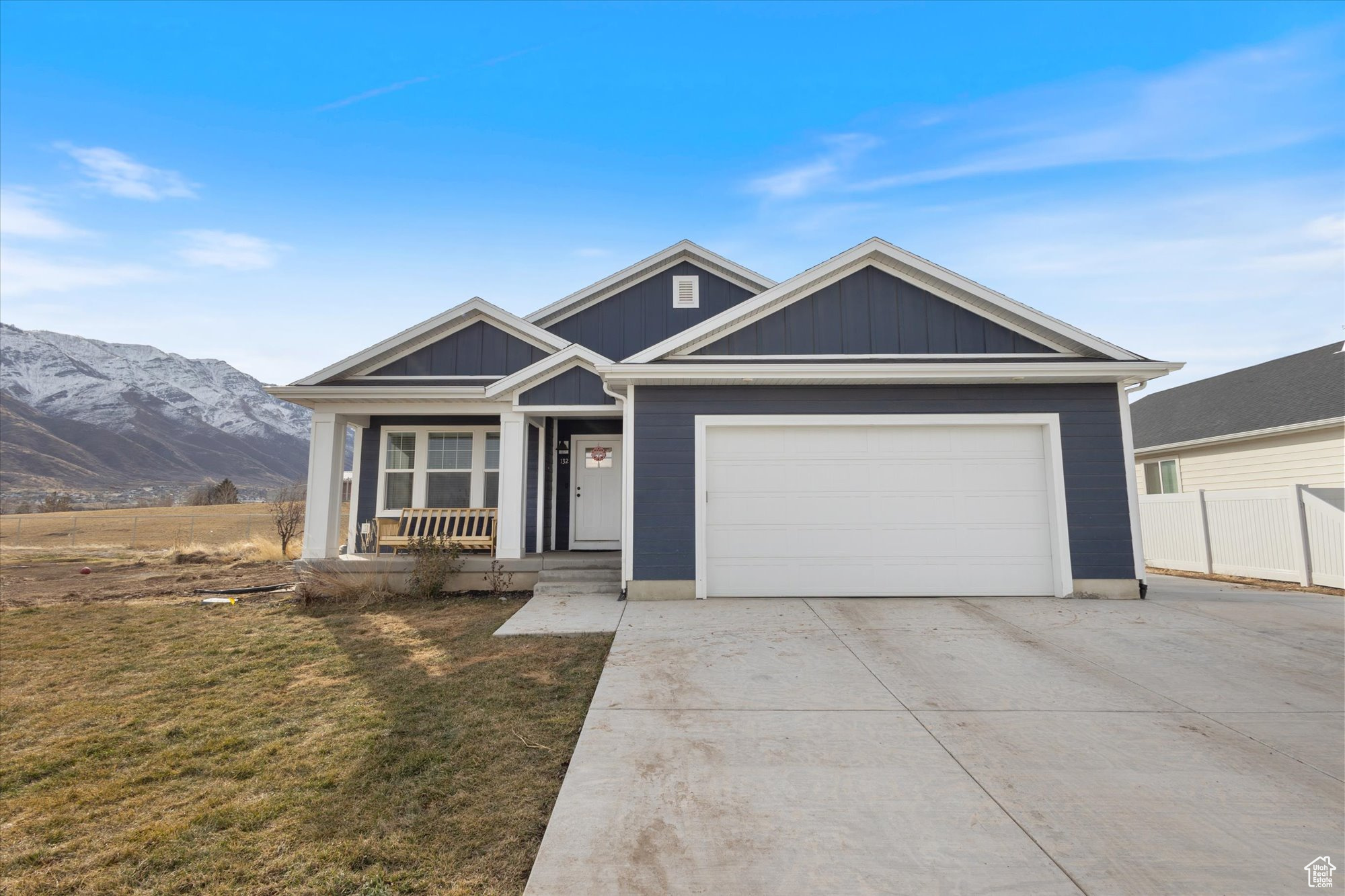 View of front of house featuring a garage, a mountain view, covered porch, and a front lawn