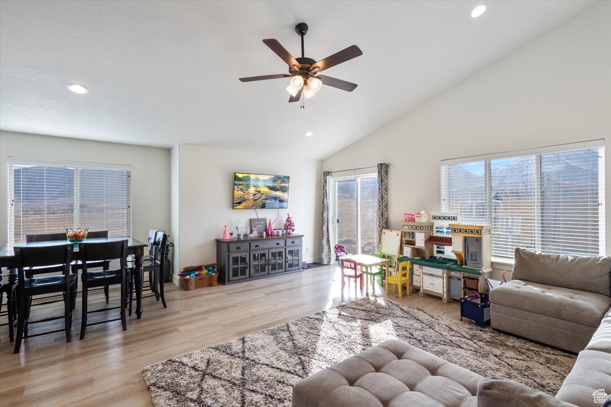Living room featuring high vaulted ceiling, light hardwood / wood-style floors, and ceiling fan