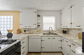 Kitchen with white cabinets, range with gas cooktop, and dishwasher