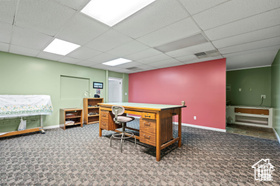 Office space with dark colored carpet and a drop ceiling
