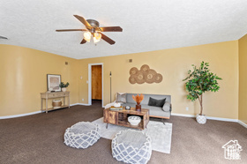 Carpeted living room featuring a textured ceiling and ceiling fan