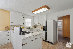 Kitchen with white cabinetry, sink, backsplash, white fridge with ice dispenser, and a textured ceiling