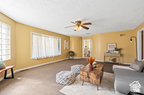 Carpeted living room with ceiling fan
