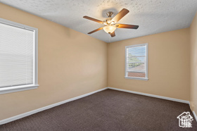 Unfurnished room with ceiling fan, a textured ceiling, and dark colored carpet