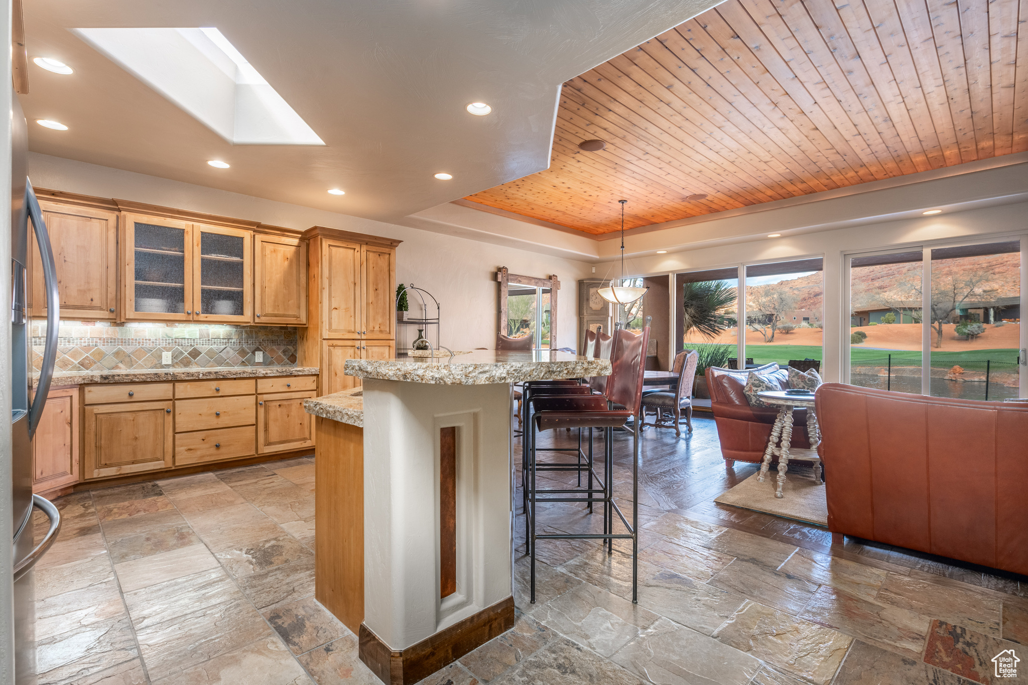 Kitchen with a kitchen island with sink, a breakfast bar area, wood ceiling, and a skylight