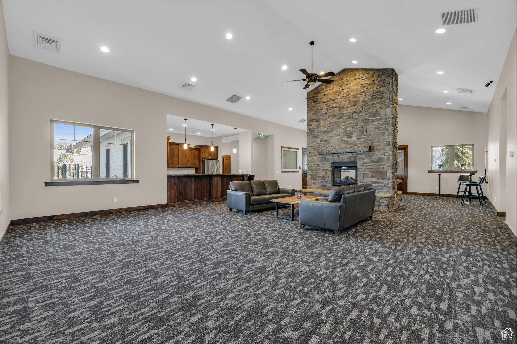 Living room featuring dark colored carpet, ceiling fan, a fireplace, and high vaulted ceiling