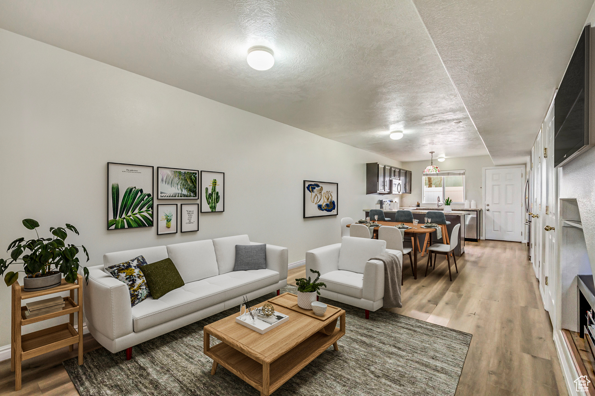 Living room featuring a textured ceiling, light wood-style flooring, and baseboards