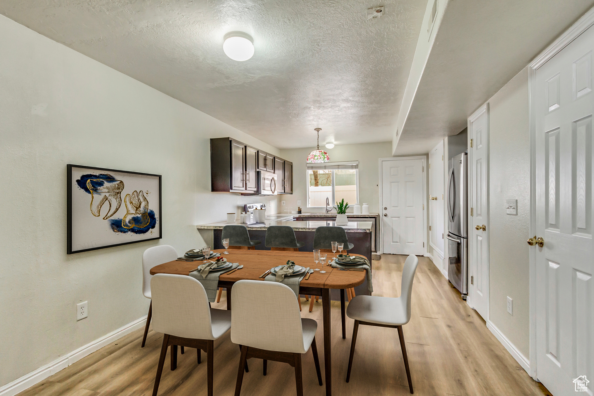 Dining area featuring light wood-type flooring, baseboards, and a textured ceiling