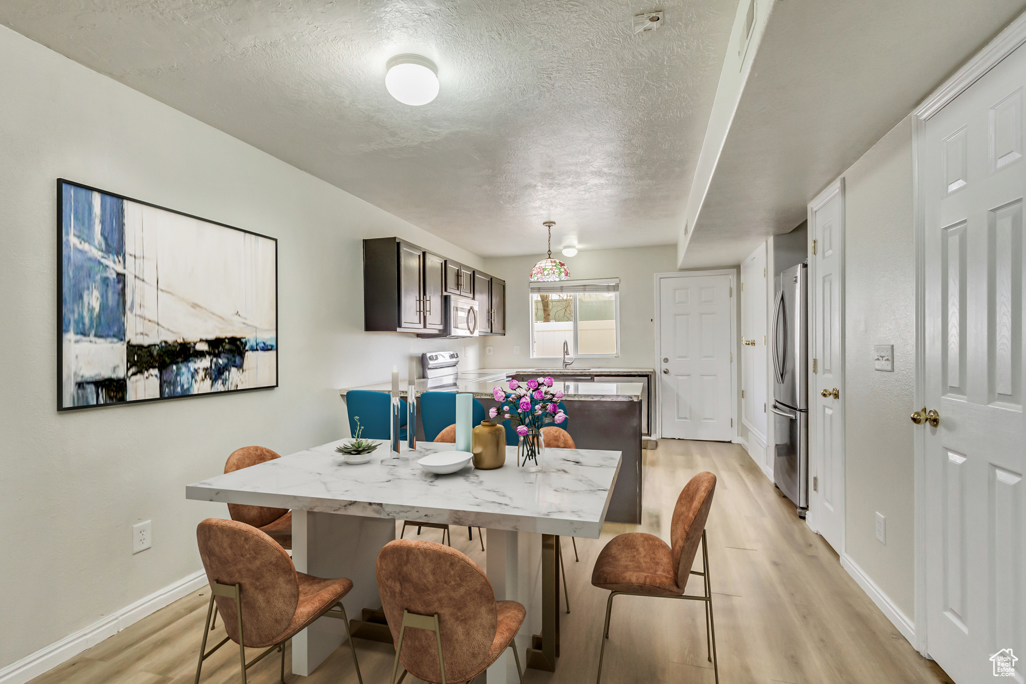 Dining space with a textured ceiling, light wood finished floors, and baseboards