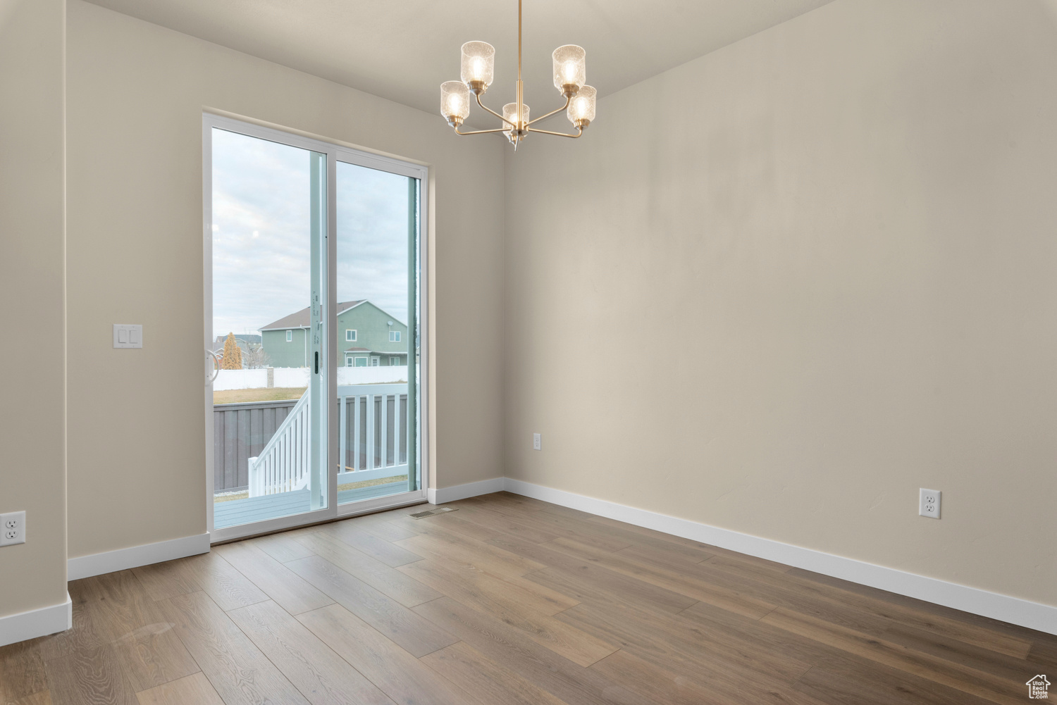 Spare room featuring an inviting chandelier and wood-type flooring