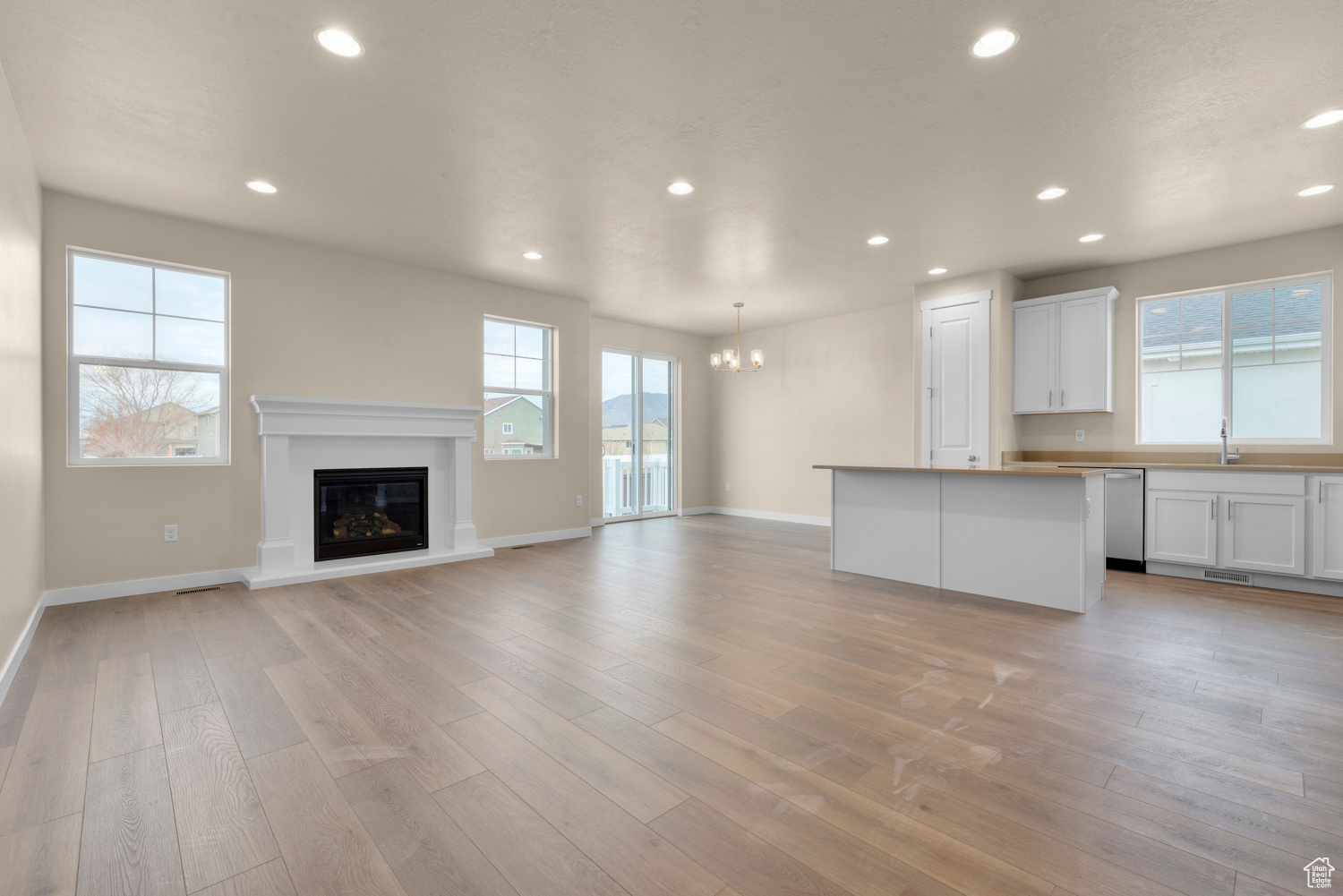 Unfurnished living room featuring a notable chandelier, a healthy amount of sunlight, sink, and light wood-type flooring