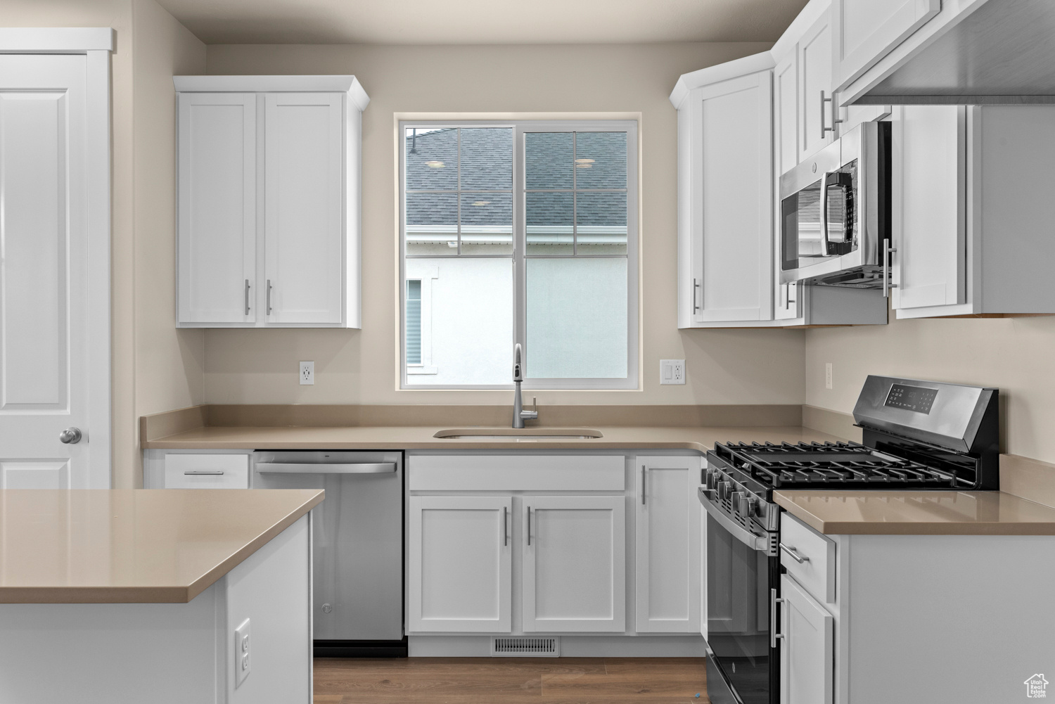 Kitchen with white cabinetry, sink, dark hardwood / wood-style floors, and appliances with stainless steel finishes