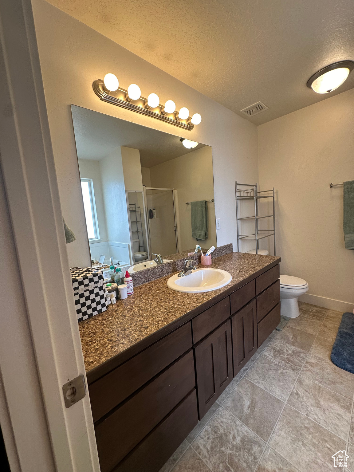 Bathroom with vanity, toilet, a textured ceiling, and walk in shower