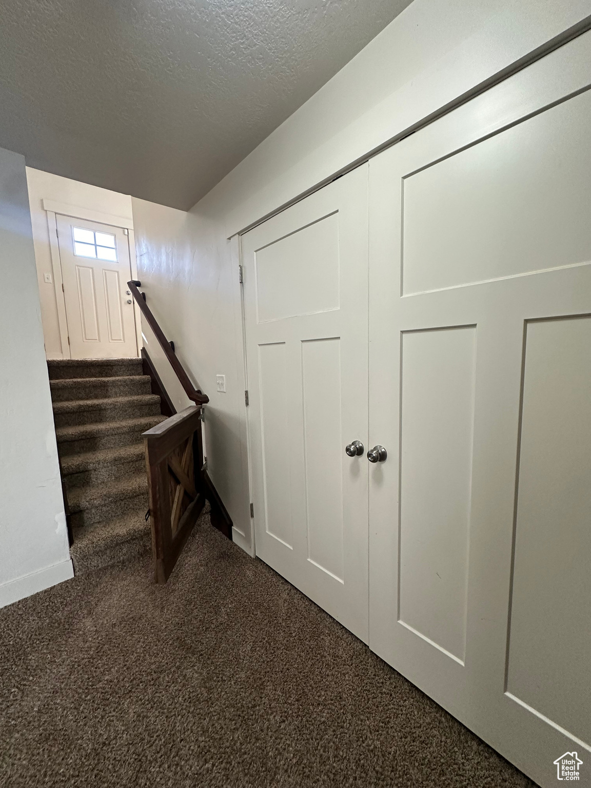 Stairway with a textured ceiling and carpet