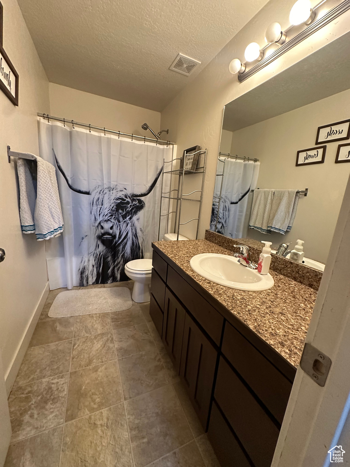 Bathroom with vanity, a shower with shower curtain, a textured ceiling, and toilet