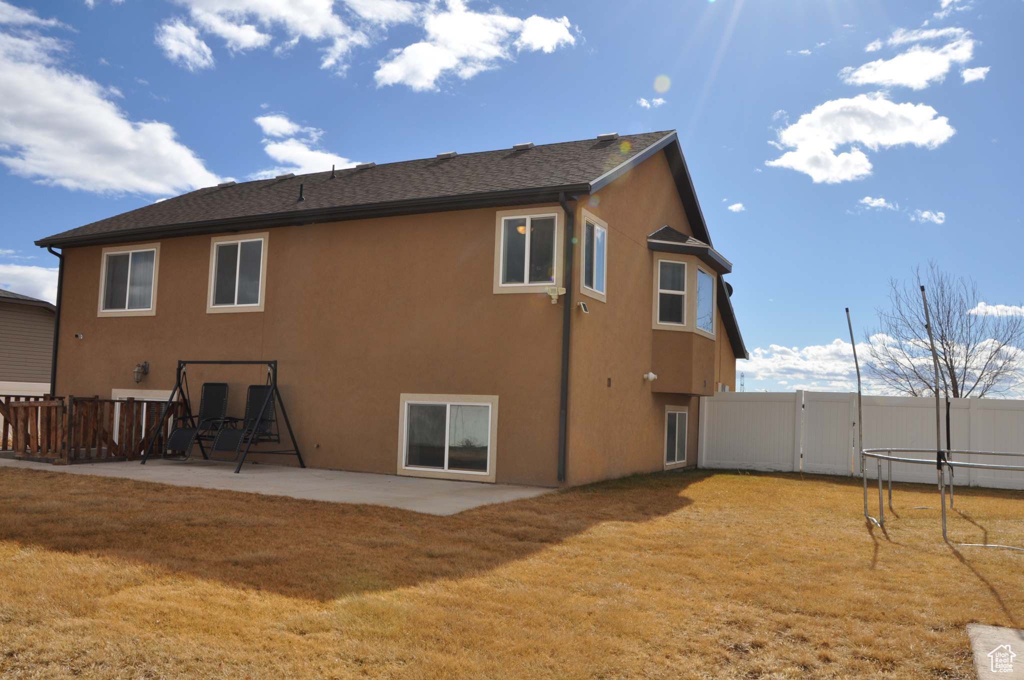 Rear view of house featuring a trampoline, a yard, and a patio