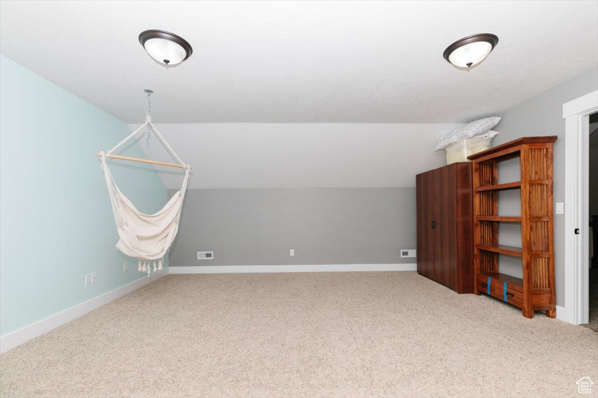 Additional living space with lofted ceiling and carpet flooring