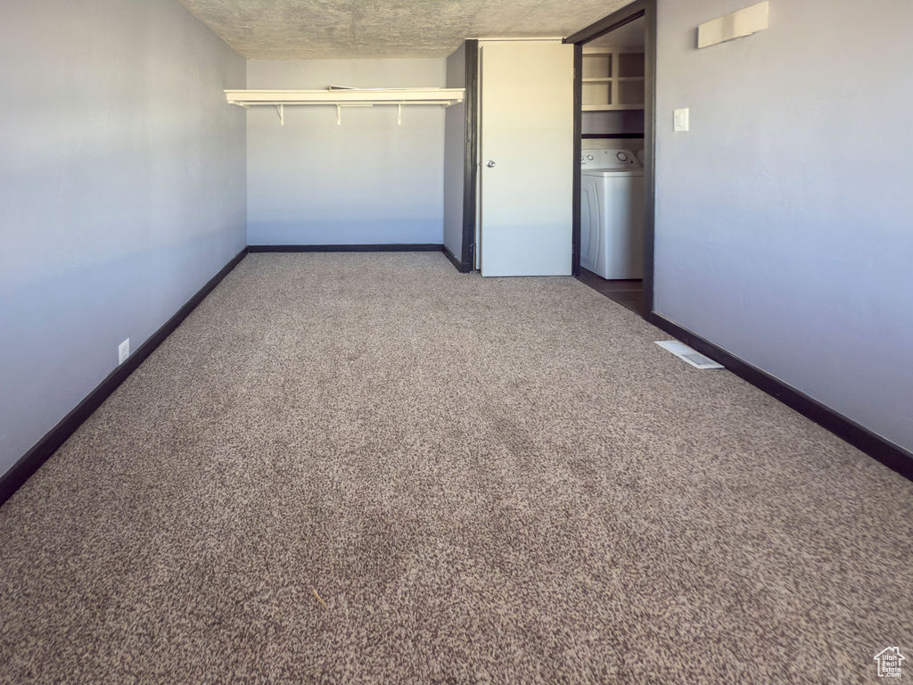Unfurnished bedroom featuring washer / clothes dryer, carpet floors, and a closet