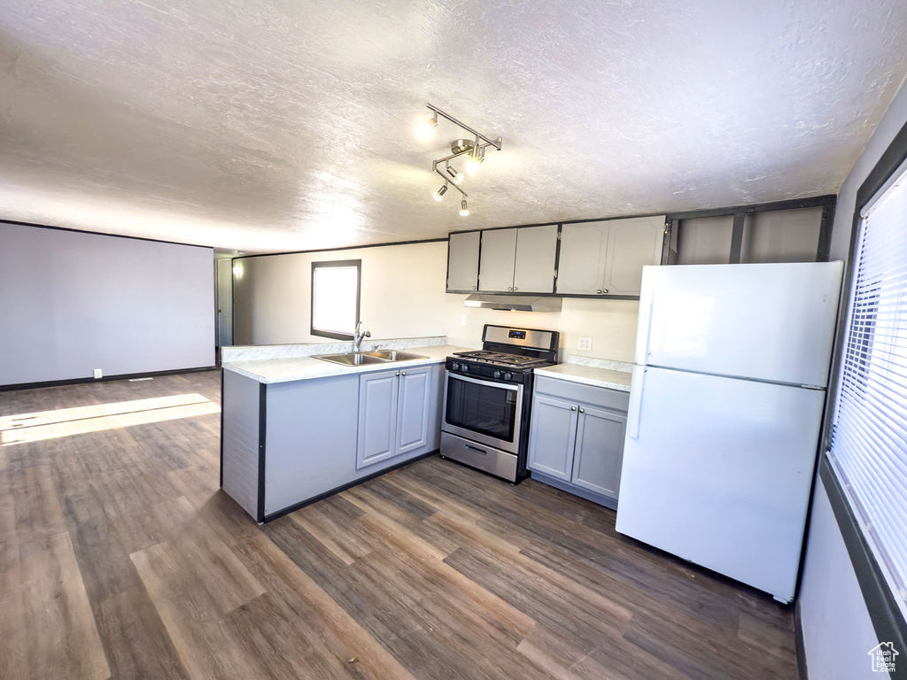 Kitchen featuring sink, stainless steel range with gas cooktop, dark hardwood / wood-style floors, gray cabinets, and white fridge